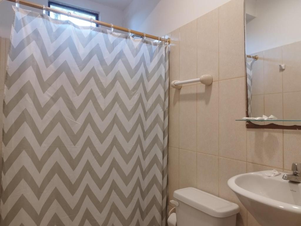 uma casa de banho com uma cortina de chuveiro, um WC e um lavatório. em Palmendros Hosteria em Montañita