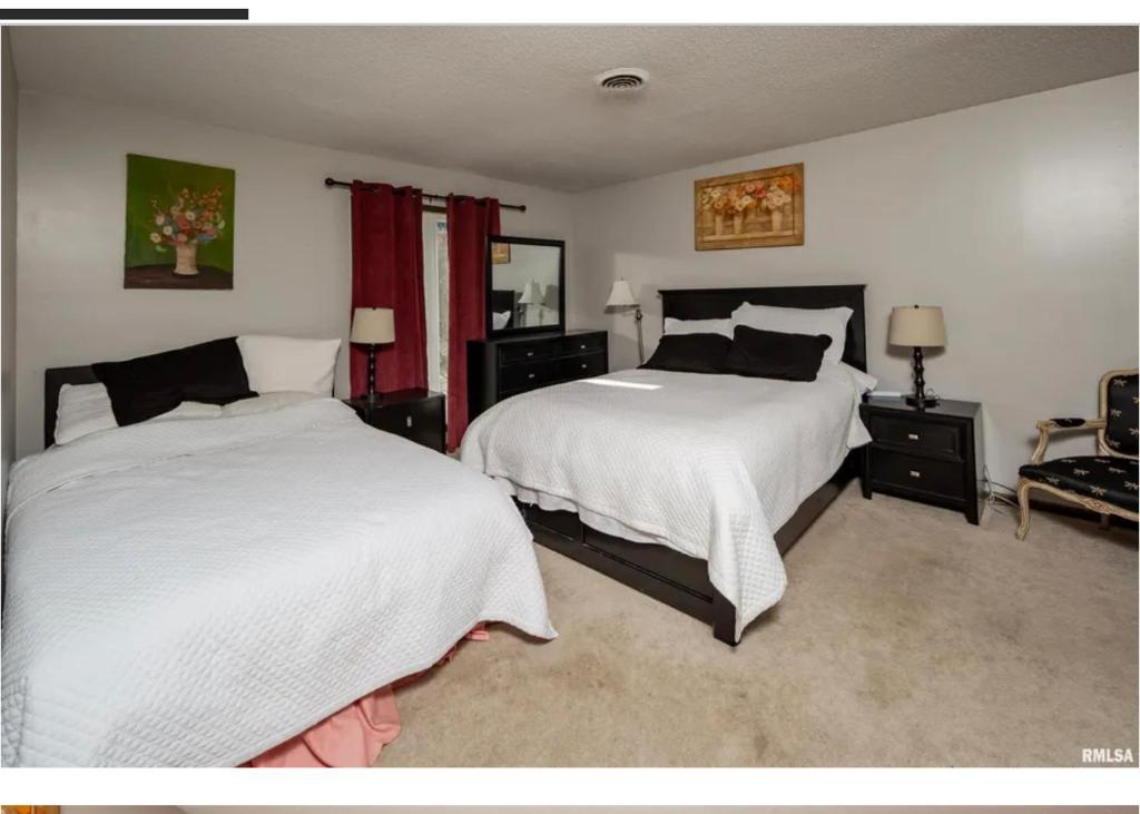 1 dormitorio con 2 camas con sábanas blancas y cortinas rojas en Luxurious condo Moline Quad Cities 4bedrooms 2 bath, en Moline