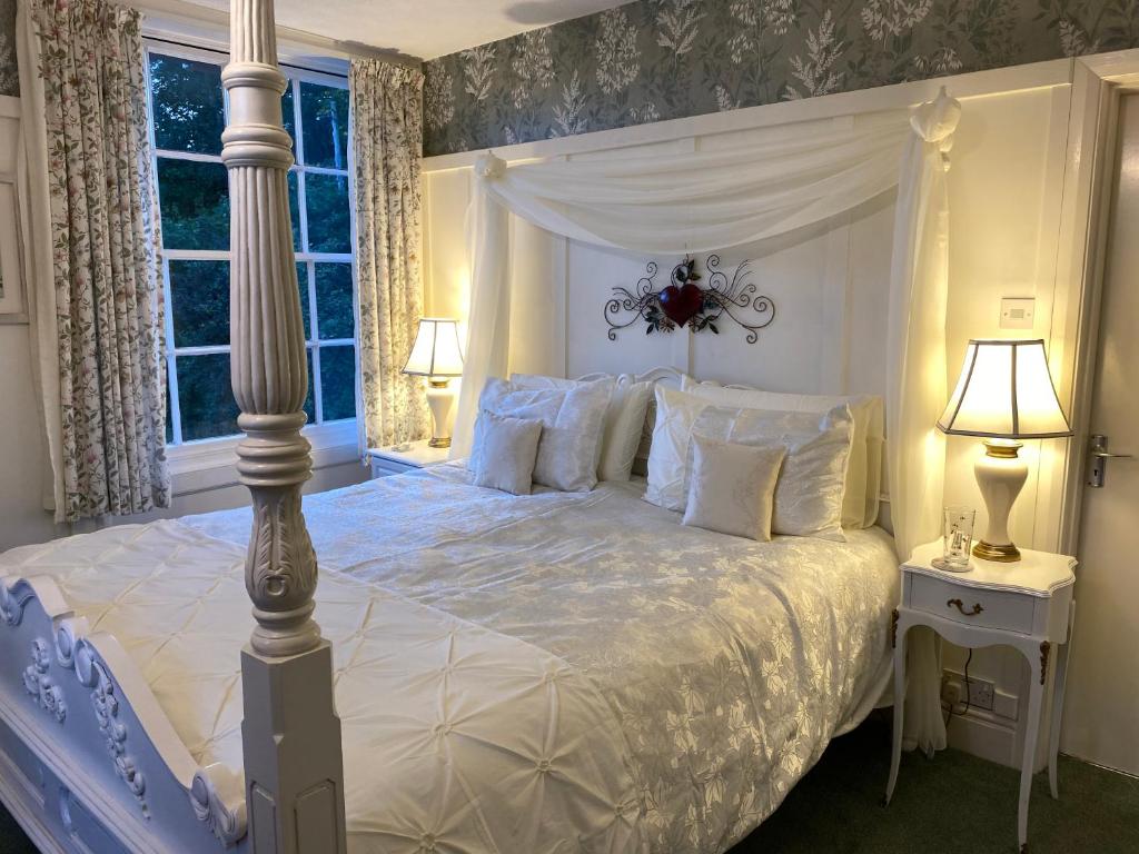 ein Schlafzimmer mit einem weißen Bett mit Baldachin in der Unterkunft Dolforwyn Hall in Montgomery