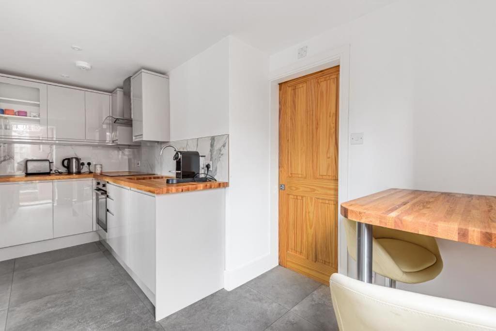 a kitchen with white cabinets and a wooden counter top at Self contained 1 bedroom in Windsor