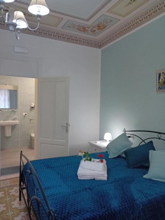 a bedroom with a blue bed and a bathroom at Regina Stella in Lascari