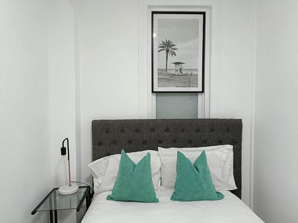 um quarto com uma cama com duas almofadas verdes em Lovely Room 1Min Walk to Station with 55Inch TV em Sydney