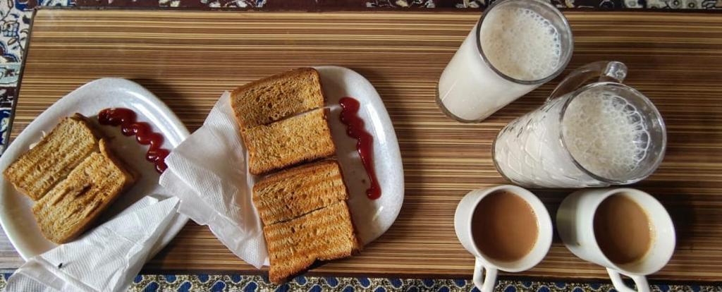 a table with two sandwiches and two cups of coffee at त्रिnity homestay in Kasol