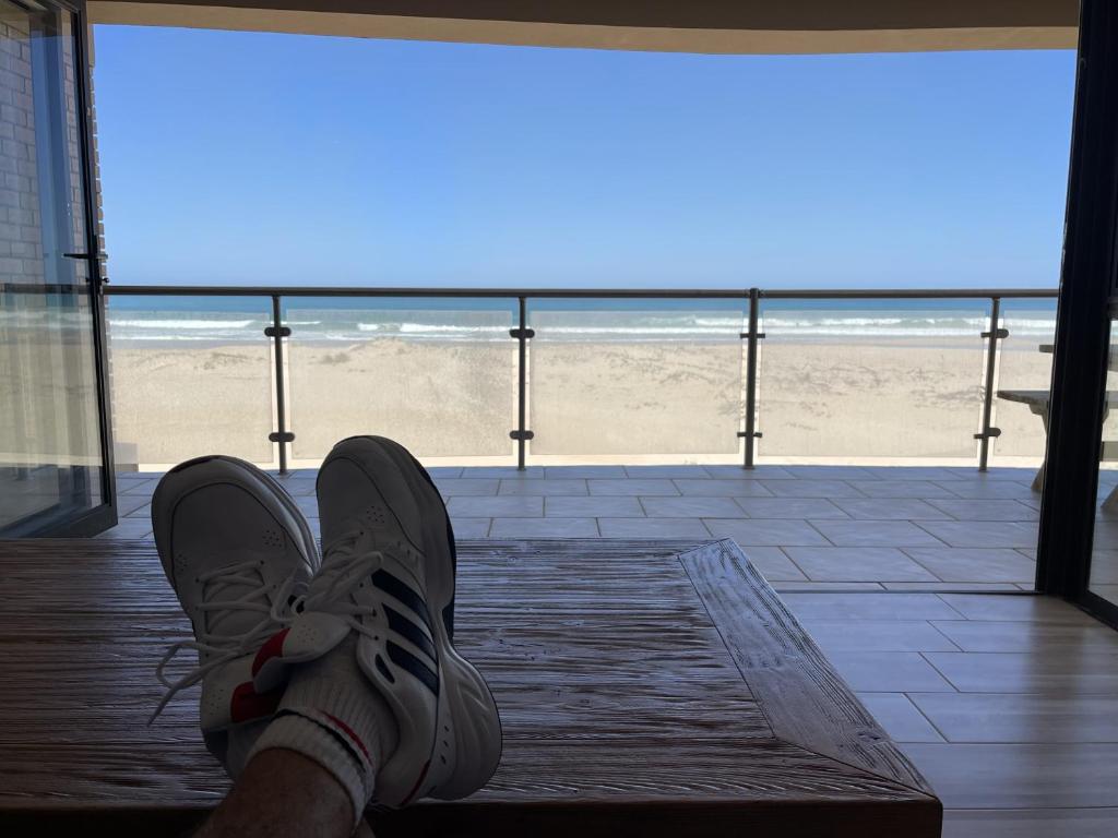 a person with their feet up on the beach at Paradise Beachfront Apartment in Jeffreys Bay