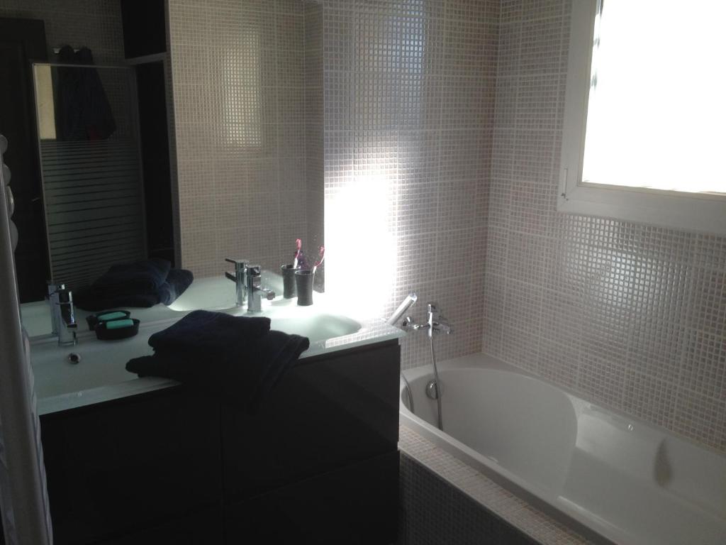 a bathroom with a white tub and a sink and a bath tub at Chambre d'hôtes l'Amaryllis in Cournon-dʼAuvergne