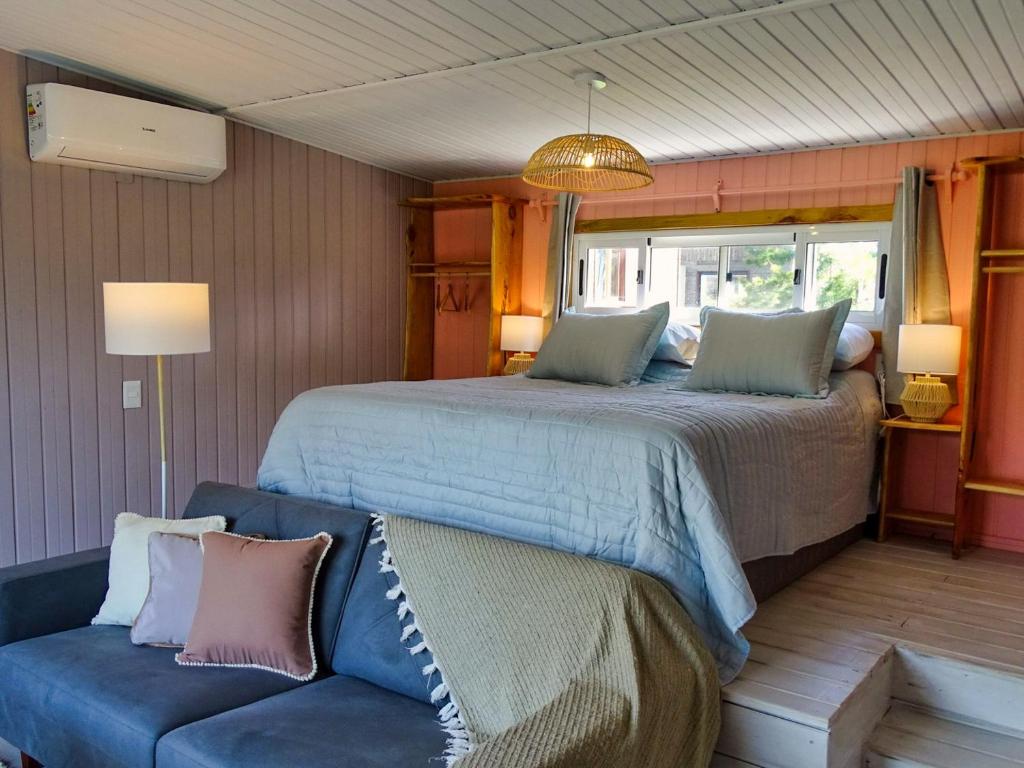 a bedroom with a large bed and a couch at Il Tano Suites in Punta Del Diablo