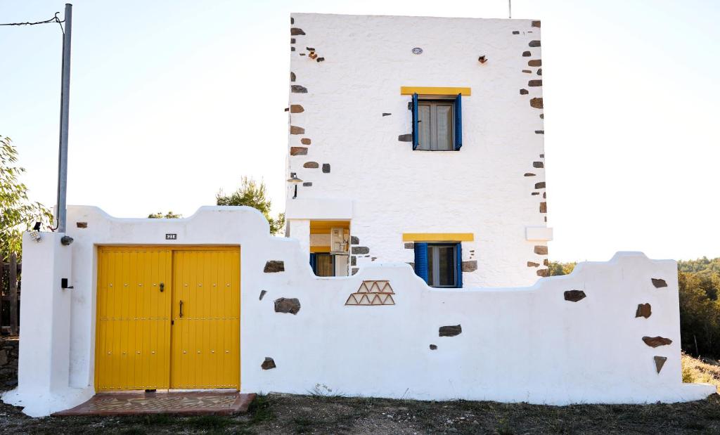 a white building with a yellow door and windows at Aspros Pyrgos in Volissos