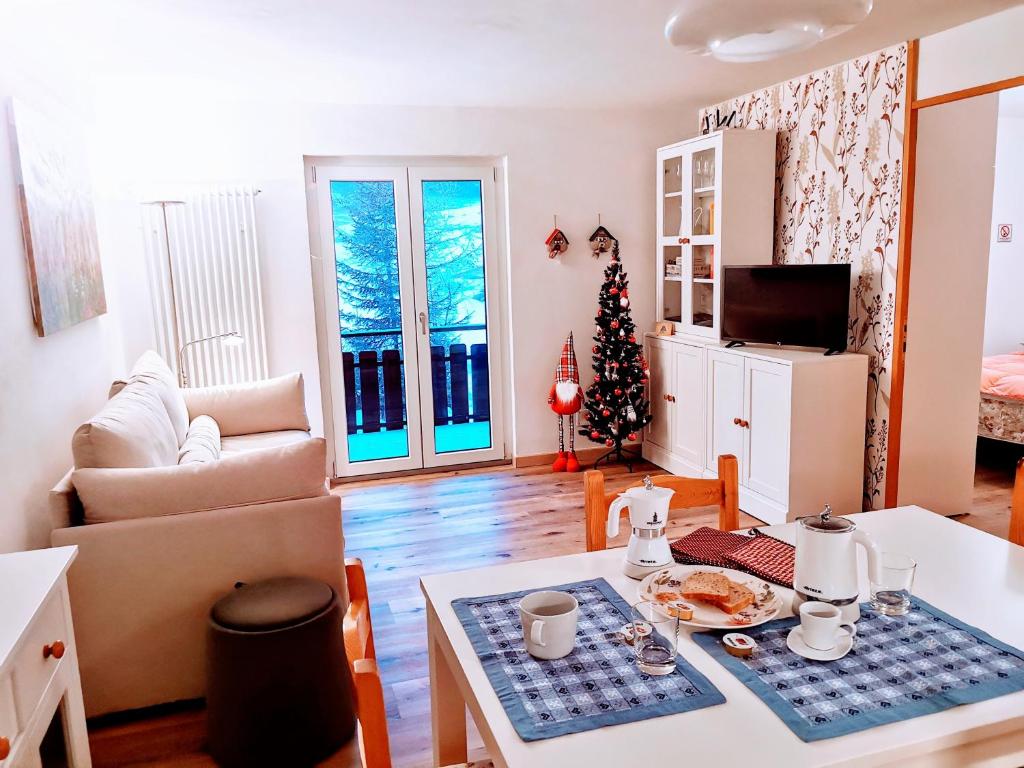 ein Wohnzimmer mit einem Weihnachtsbaum und einem Tisch in der Unterkunft Casina Alpina sugli impianti Passo S Pellegrino in Passo San Pellegrino