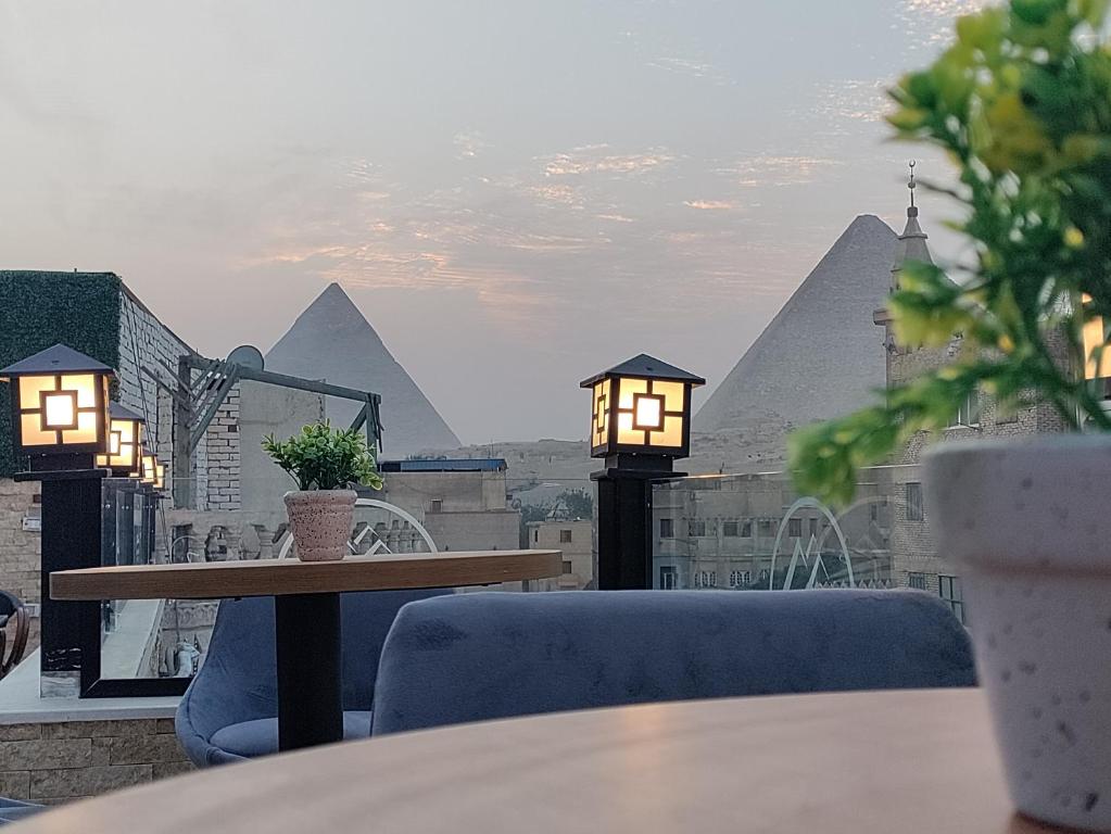 Locanda Pyramids Hotel في القاهرة: طاولة وكراسي على شرفة مع الاهرامات