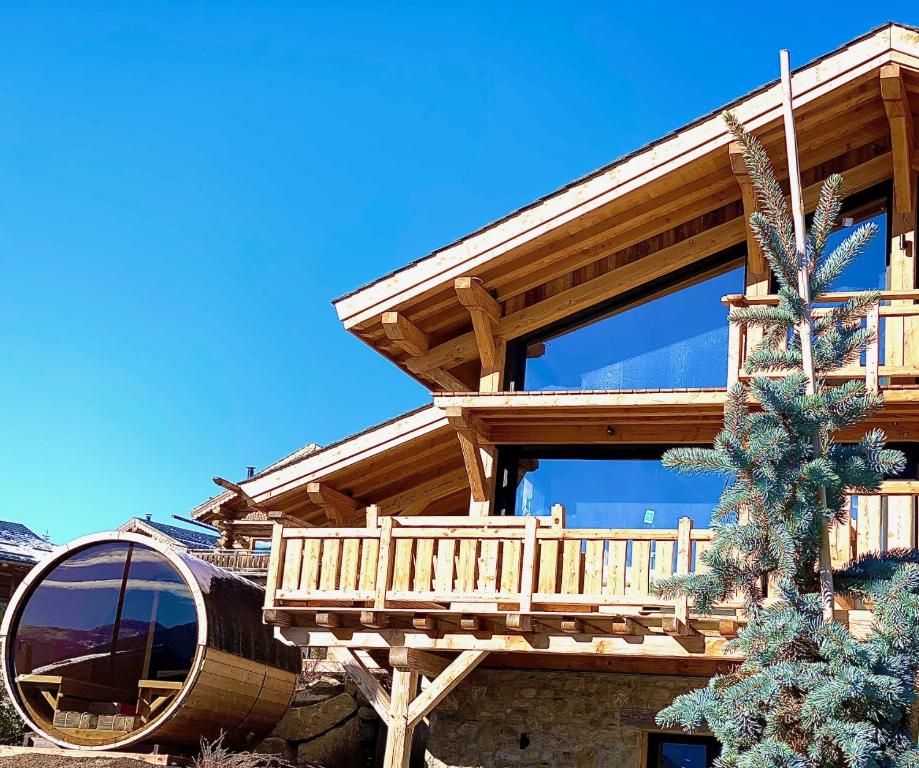 una casa de madera con una terraza a un lado. en Chalet Aguila - Jacuzzi et sauna panoramique - Construit en 2023, en Bolquere Pyrenees 2000