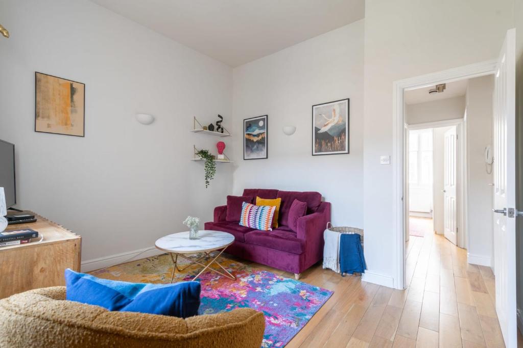 uma sala de estar com um sofá roxo e uma mesa em Fantastic Earls Court Flat em Londres