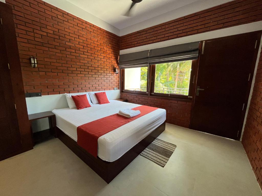 een slaapkamer met een bed en een bakstenen muur bij Coastal Hideaway in Midigama East