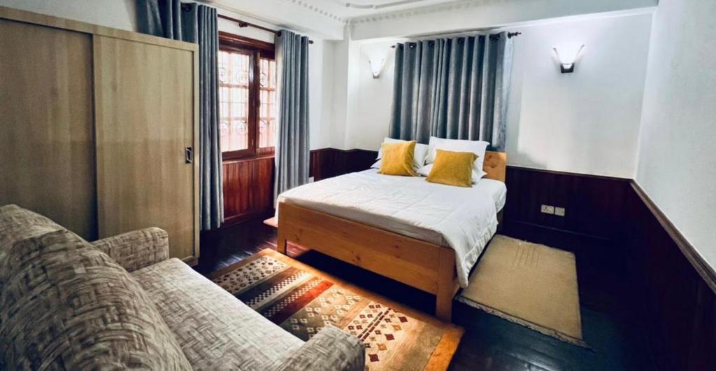 um pequeno quarto com uma cama e um sofá em Makach House- Traditional Boutique House with Garden em Kathmandu