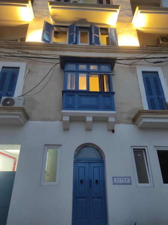 a white building with blue windows and a door at One in Se7en in St. Julianʼs