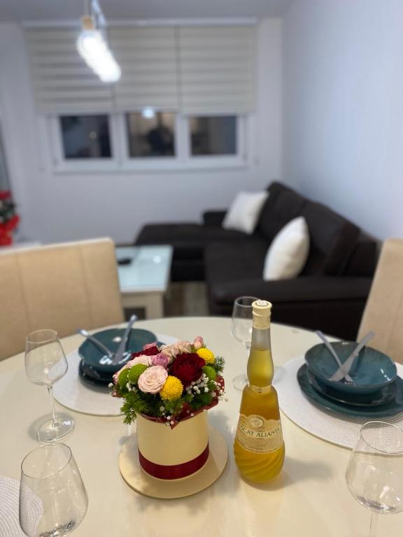 a table with a flower arrangement and a bottle of wine at Apartman Alexandra in Ruma