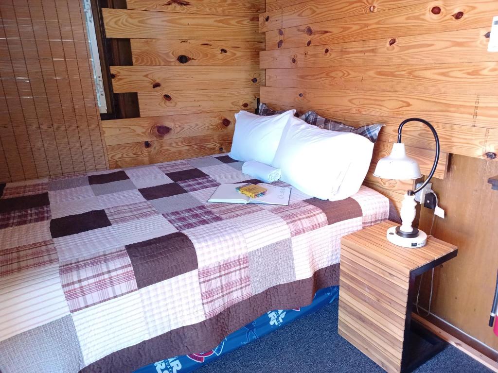 a bedroom with a bed with a lamp and a book at Cabin by the Pool 