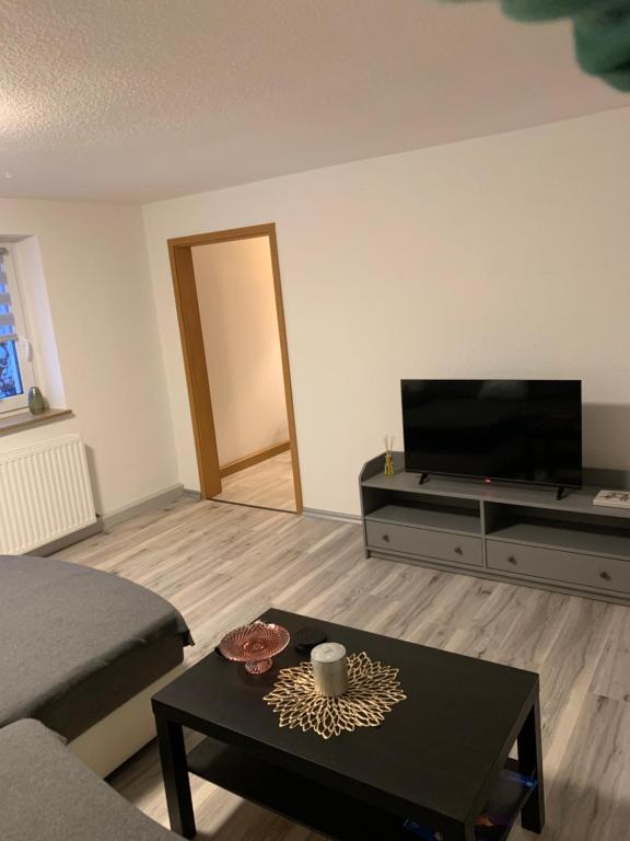 uma sala de estar com uma televisão e uma mesa de centro em Ferienwohnung Maryna em Zwönitz