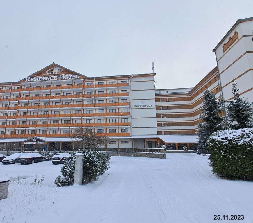 a large hotel with a parking lot in the snow at Apartman MARLEA in Donovaly