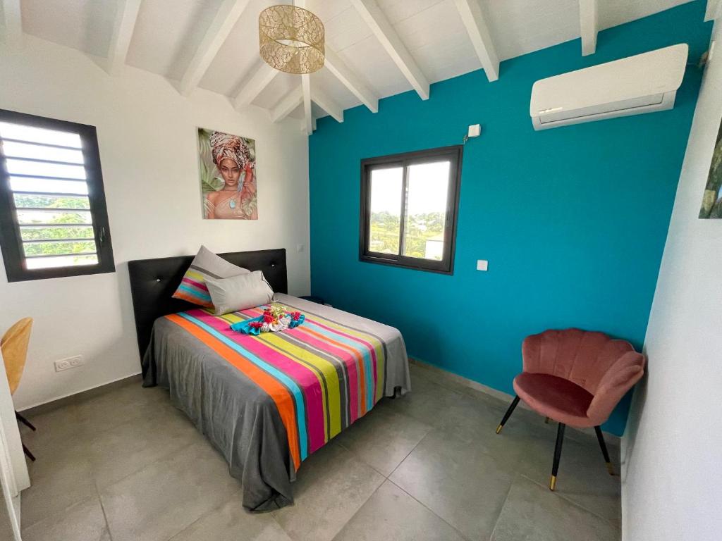 een slaapkamer met een bed en een blauwe muur bij Les cocotiers d'Aladya in Lamentin