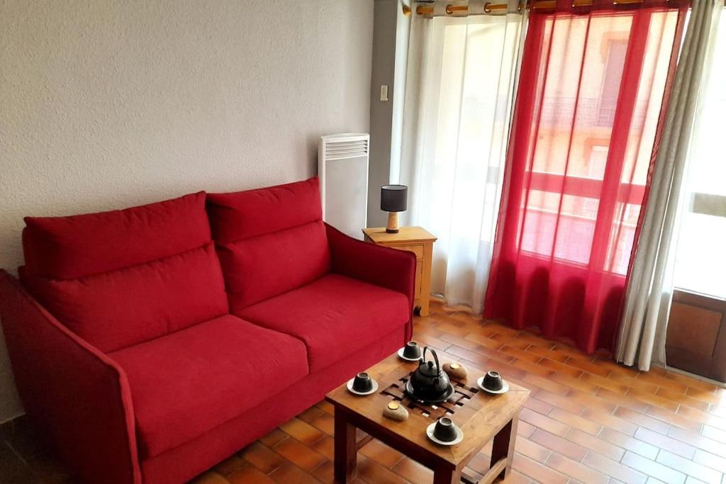 un salon avec un canapé rouge et une table basse dans l'établissement Appartement serre chevalier 1200, à Briançon