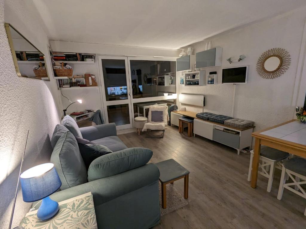 a living room with a blue couch and a table at Appartement cosy au pied des pistes in Corrençon-en-Vercors