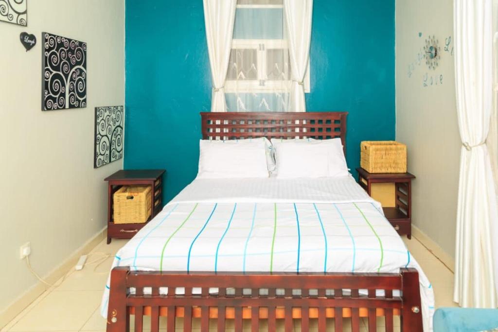 a bedroom with a bed with a blue wall at City Oasis Home Stays by Siima in Kampala