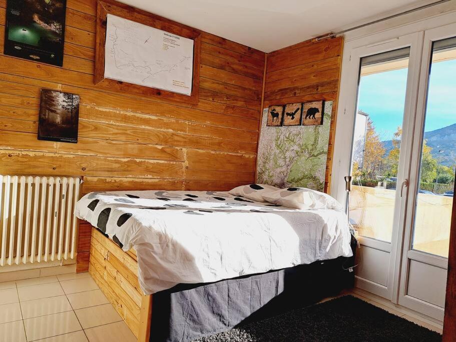 1 dormitorio con 1 cama en una habitación con paredes de madera en Appartement entier proche centre-ville, en Millau