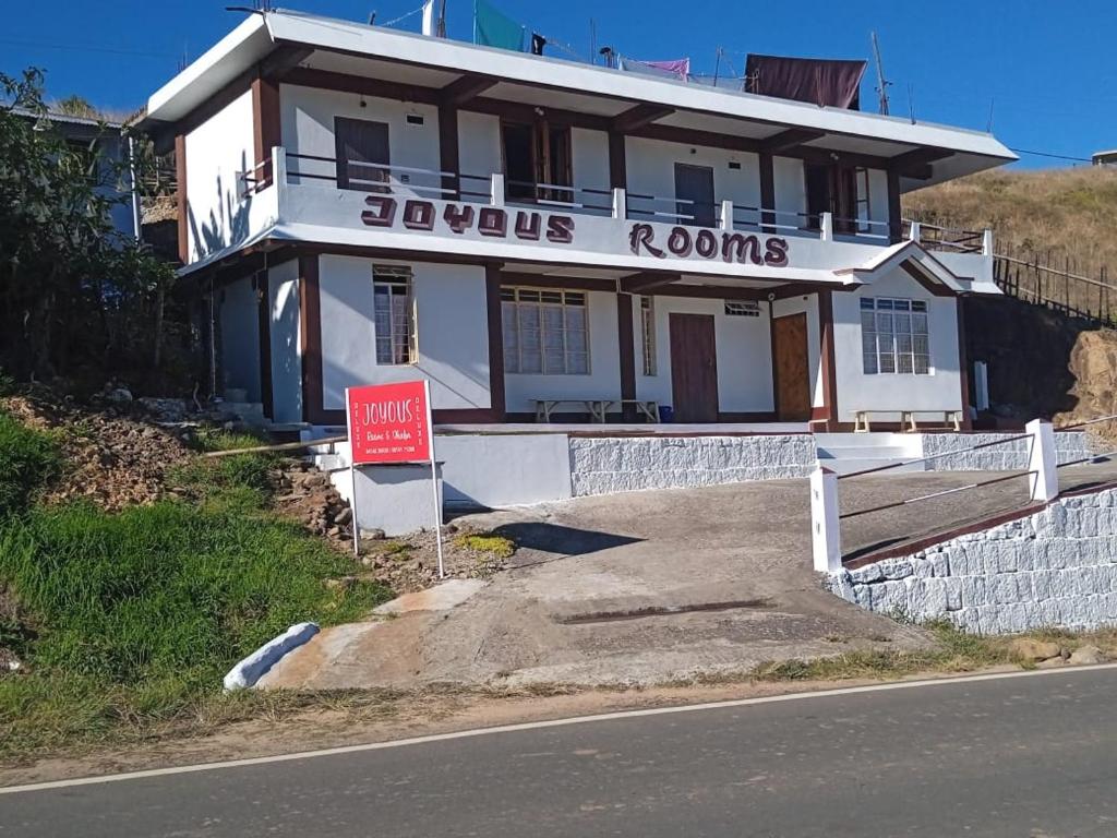 a white house with a sign in front of it at Joyous Rooms in Cherrapunji