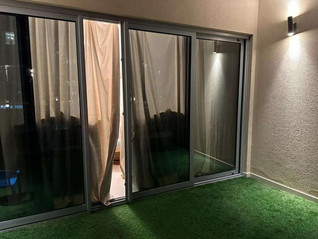 Habitación con puertas de cristal y alfombra verde. en Sherina Plaza 2 Flat 103 en Dubái