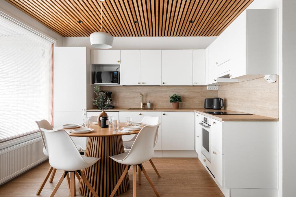 a kitchen with white cabinets and a wooden ceiling at Kingwest Villa - free parking, sauna & 5 bedrooms in Tampere
