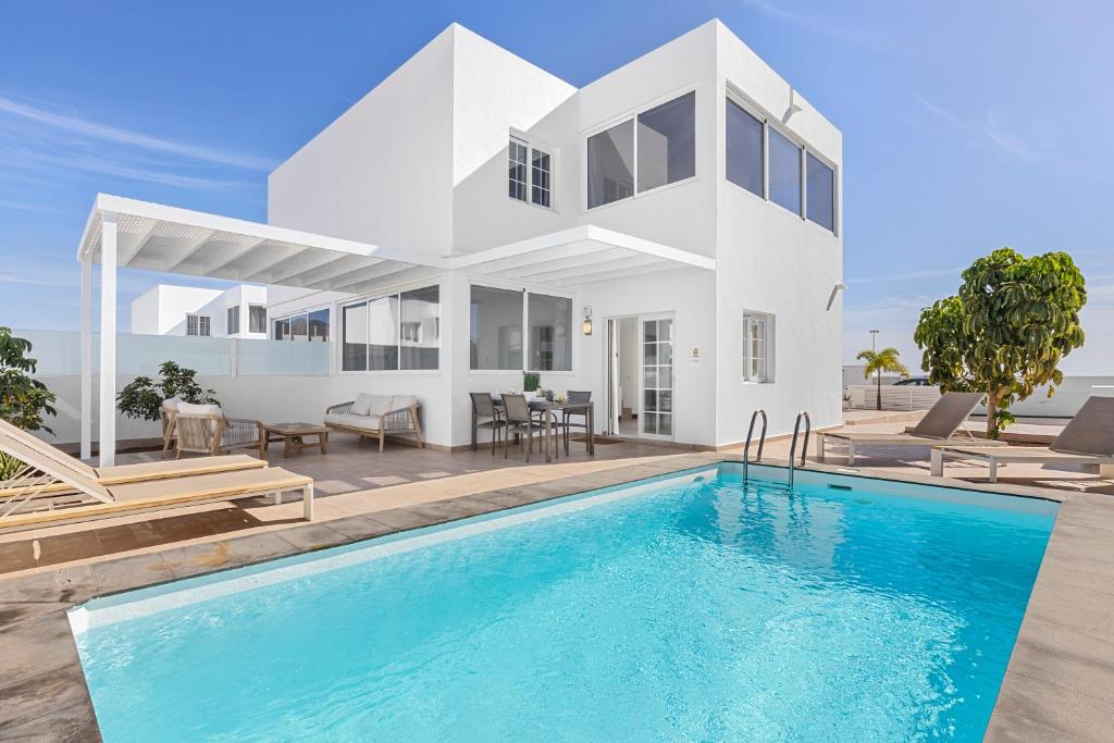 a villa with a swimming pool in front of a house at Villa Atlántica - Heated pool in Playa Blanca in Playa Blanca