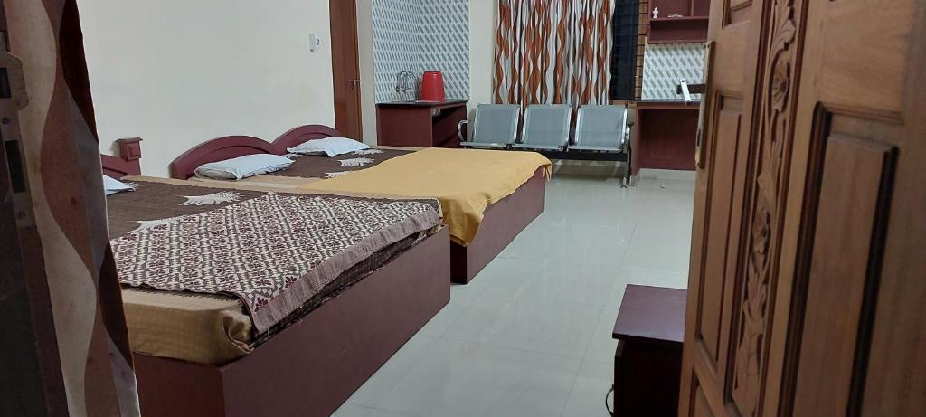 two beds in a room with chairs in it at Guruvayur Adithya in Guruvāyūr