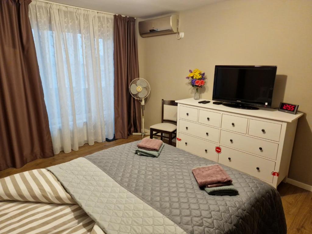 een slaapkamer met een bed en een dressoir met een tv bij Варна Младост 143 in Varna