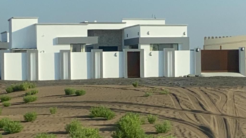 ein Gebäude inmitten eines Feldes mit Schmutz in der Unterkunft Dune Chalet شالية ديون in Al Wāşil
