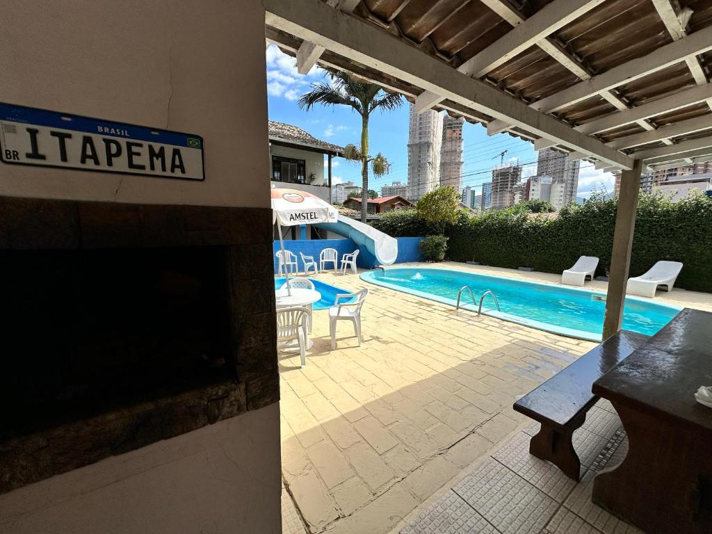 een zwembad met een tafel en stoelen naast een gebouw bij Hotel D'Luz in Itapema