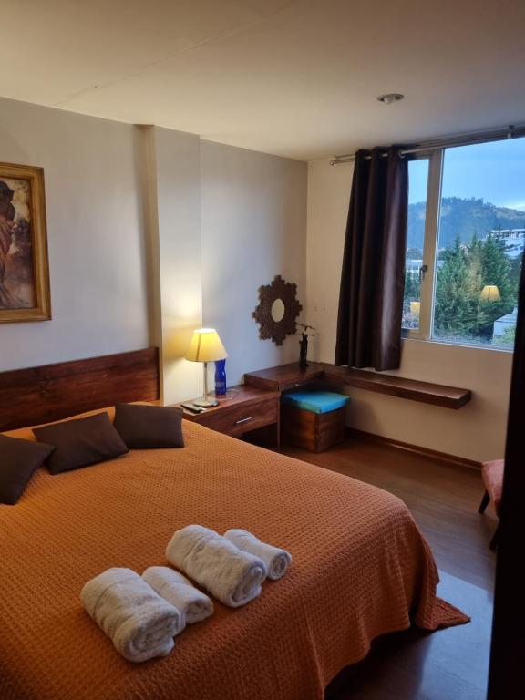 1 dormitorio con 2 toallas en una cama con ventana en French Suite Tamayo, en Quito