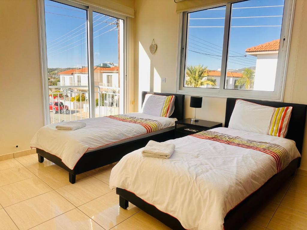 2 camas en una habitación con ventanas grandes en Athena Villa, en Lárnaca