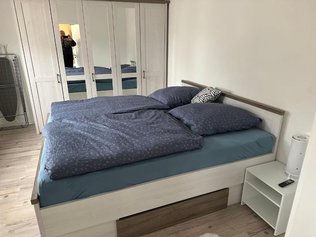 ein Bett mit blauer Bettwäsche und Kissen in einem Schlafzimmer in der Unterkunft Ferienwohnung 2, 1. OG Nähe Augenklinik in Sulzbach