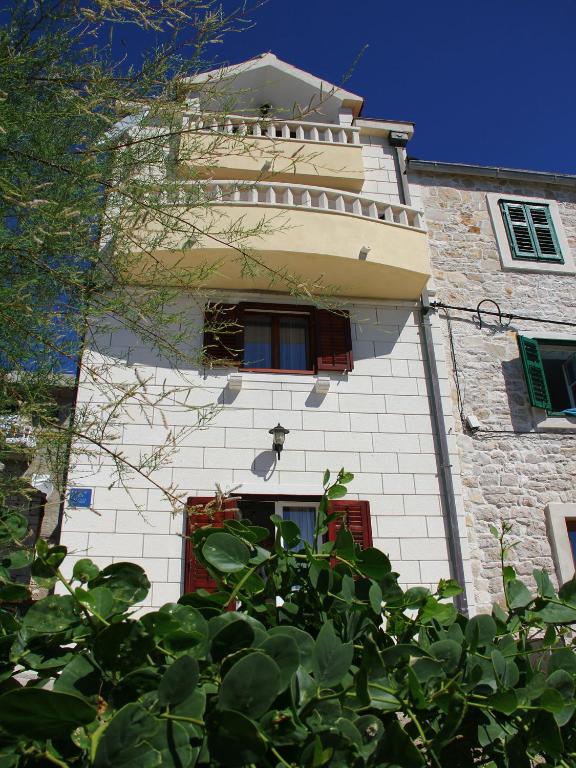 a white building with a red door and windows at Holiday Home Blaž in Primošten