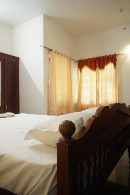 um quarto com uma cama com lençóis brancos e uma janela em Joby homestay Kadamakudy em Ernakulam