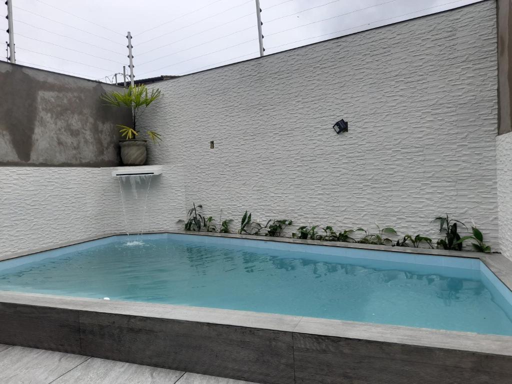 een groot zwembad voor een bakstenen muur bij Casa de praia com piscina in Itanhaém