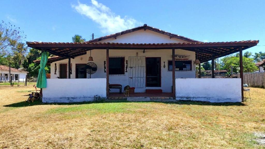 a small white house with a roof at Casa em Soure Ilha de Marajó. in Soure