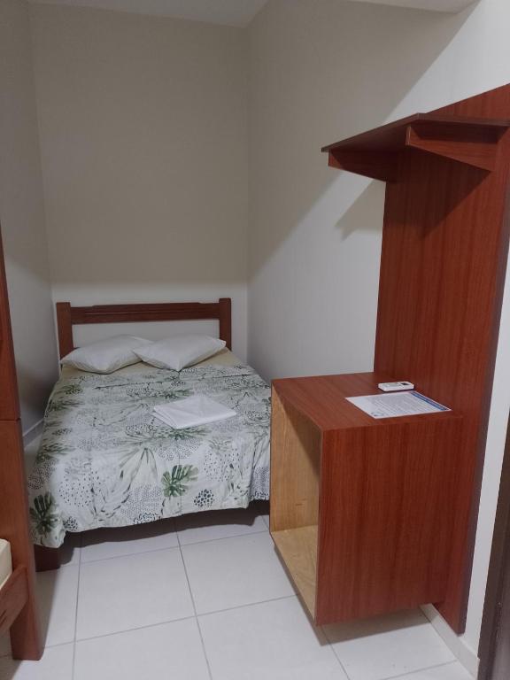 een kleine slaapkamer met een bed en een houten kast bij Pousada Mundo Novo in Aparecida