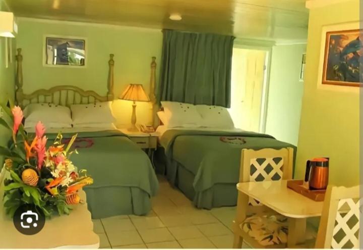 a bedroom with two beds and a table with a vase of flowers at Big Apple Hotel in Montego Bay