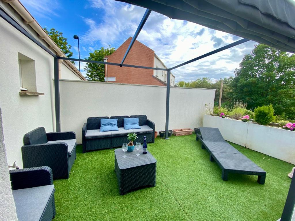 un patio con 2 sofás y una mesa en el césped en Appartement terrasse proche Versailles, en Élancourt