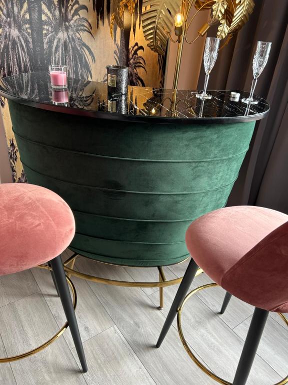 a table with two pink chairs and a green barrel at Villa Maxima mit Terrasse, Klimaanlage und Sauna in Bad Wildungen