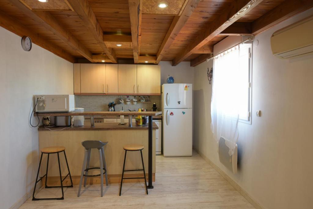 a kitchen with a refrigerator and two bar stools at VENEZ SEJOURNER A GRUISSAN ....PLAGE DES CHALETS in Gruissan
