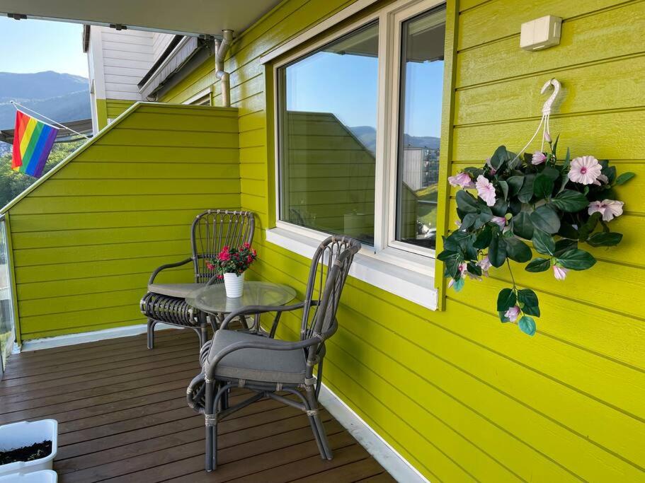 una casa amarilla con una mesa y sillas en un porche en 84m2 3 sleeping rooms which direct traffic to airport and city center en Bergen