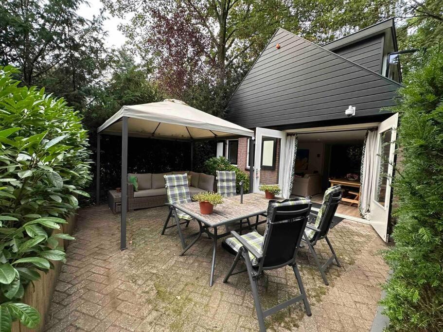 een patio met een tafel en stoelen en een parasol bij Private House ‘Het Dwerghuys’ - also longstays in Doorn