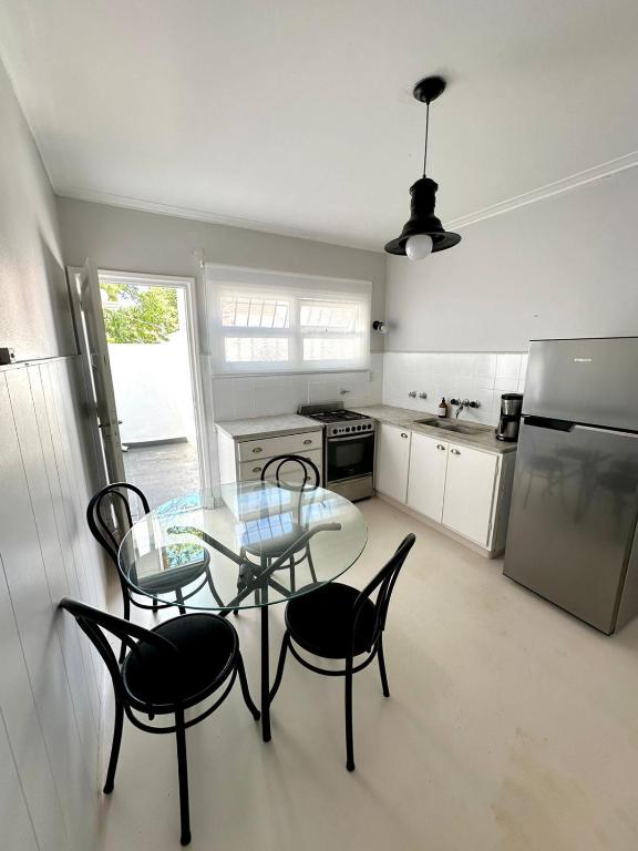 a kitchen with a glass table and chairs and a refrigerator at C&M in Mar del Plata